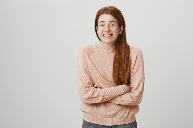 Worried redhead girl cross arms chest, smiling nervously