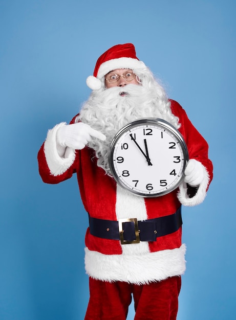 Free photo worried santa claus holding clock