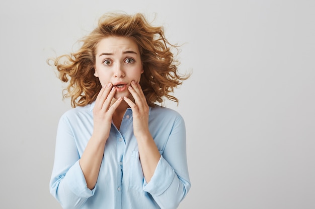 Worried and scared curly-haired girl gasping concerned