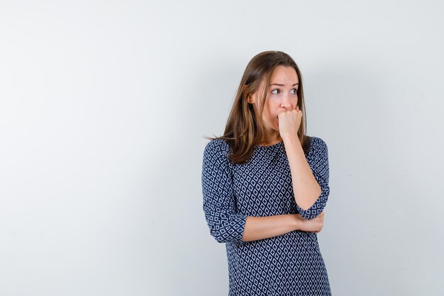 心配している女性は白い背景の上の口に彼女の拳を置いています