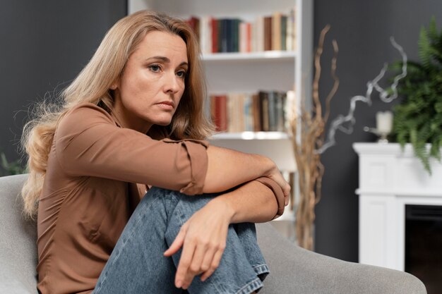 Обеспокоенная женщина, сидящая на диване