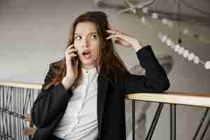 Free photo worried young businesswoman at cafe talking by phone