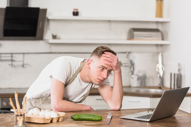 Free photo worried young man with hand on his forehead looking at digital tablet