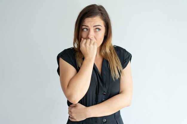 Worried young woman biting nails while having anxiety. 