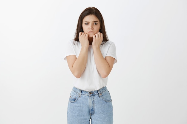 Worried young woman posing against white wall