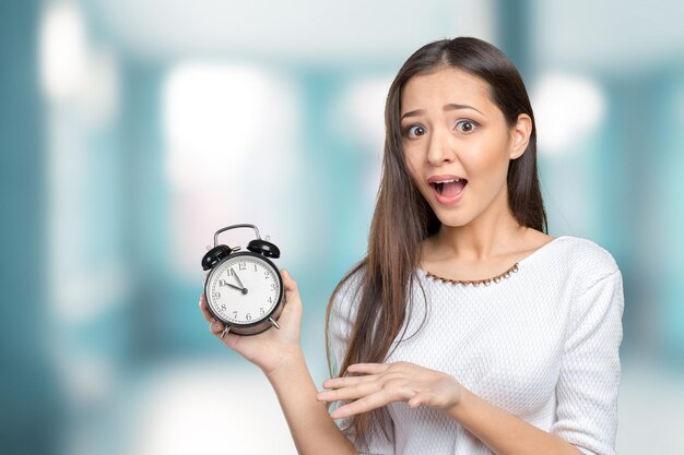 Worried youngwoman with alarmclock