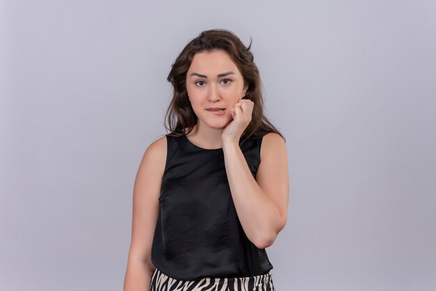 Worrying caucasian young girl wearing black undershirt scratch cheek on white background