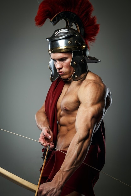 Wounded gladiator with bow isolated on grey.