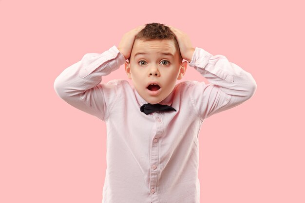 Wow. Attractive male half-length front portrait on pink  backgroud. Young emotional surprised teen boy standing with open mouth