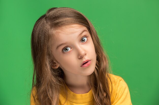 Wow. Beautiful female front portrait isolated on green  wall. Young emotional surprised teen girl standing with open mouth. Human emotions, facial expression concept.