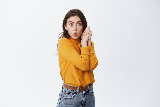 Wow interesting Excited brunette girl seeing something cool checking out shop sale pucker lips and staring at camera amazed standing on white background