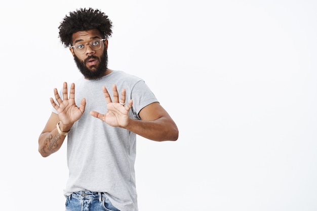 Free photo wow slow down. portrait of intense displeased and shocked, freak out african american male friend with curly hair and beard raising hands in calming gesture making warning and giving refusal