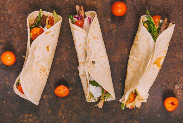 Foto gratuita avvolgere tacos di manzo messicano con pomodori su sfondo arrugginito