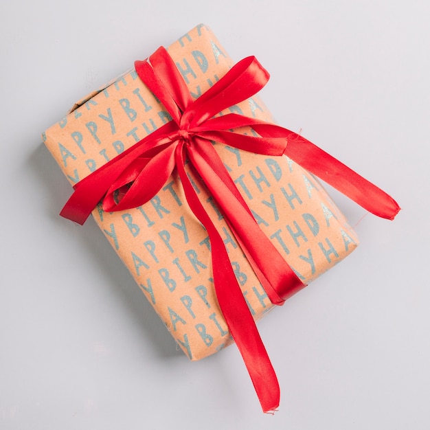 Wrapped gift box with red ribbon as a happy birthday present on white background