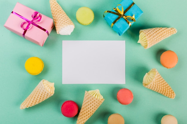 Wrapped gift boxes; macaroons and waffle with aalaw around the white paper on mint green backdrop