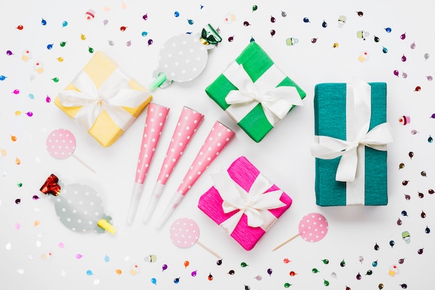 포장 된 선물 상자; 파티 혼 송풍기; 흰색 배경에 색종이로 둘러싸인 소품