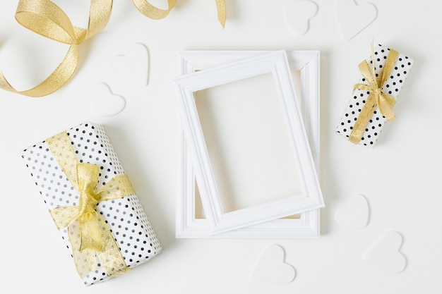 Wrapped gift boxes with heart shapes and wooden frames for wedding on white backdrop