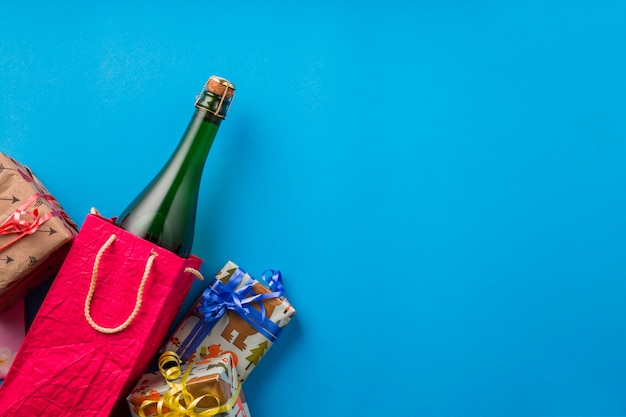 Wrapped gift and champagne bottle over blue background 