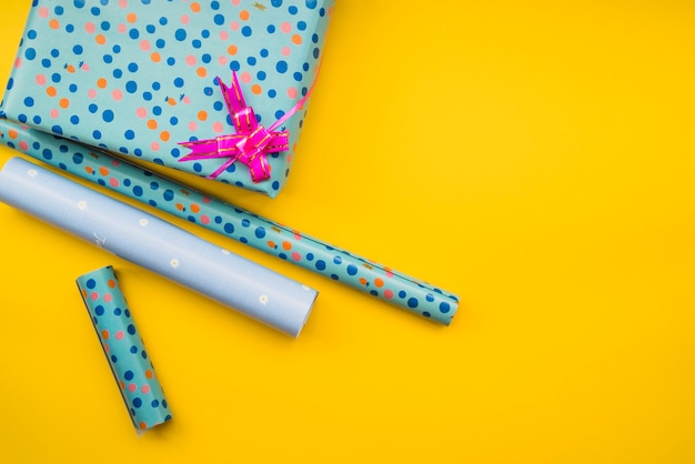 Wrapped gift paper with gift box on yellow background