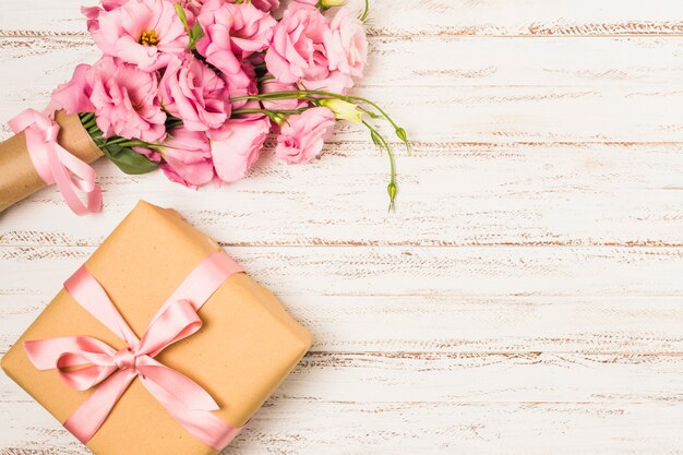 흰색 이전 테이블에 래핑 된 핑크 eustoma 꽃과 선물 상자
