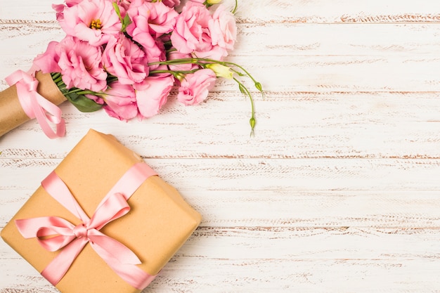Завернутая розовая эустома цветок и подарочная коробка на белом старом столе