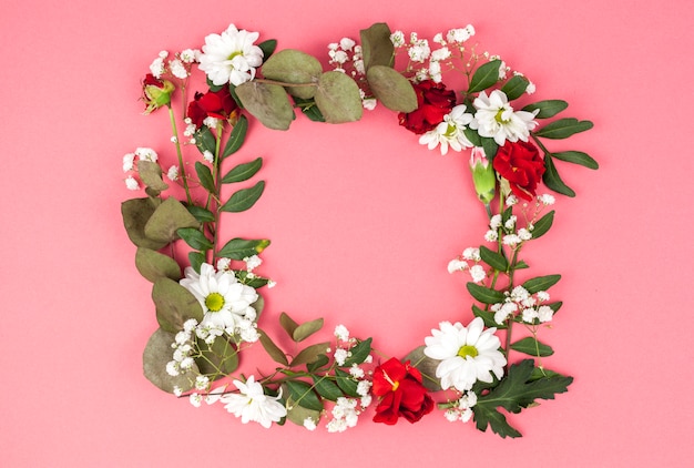 Wreath made from red and white flowers in front of peach background