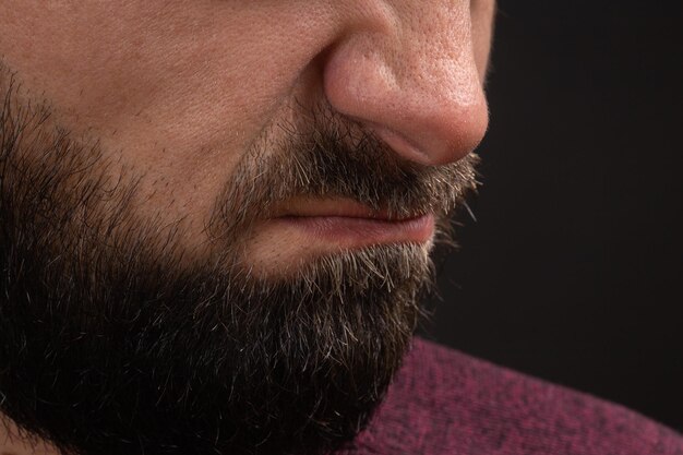 Wrinkled grimace of danger closeup on face and lips of young unrecognizable man with black beard and... Premium Photo