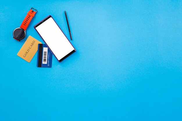 Wristwatch; cellphone; and credit card on blue surface for online shopping 