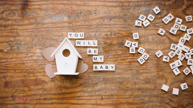 Foto gratuita scrivendo di venire bambino vicino casa di legno