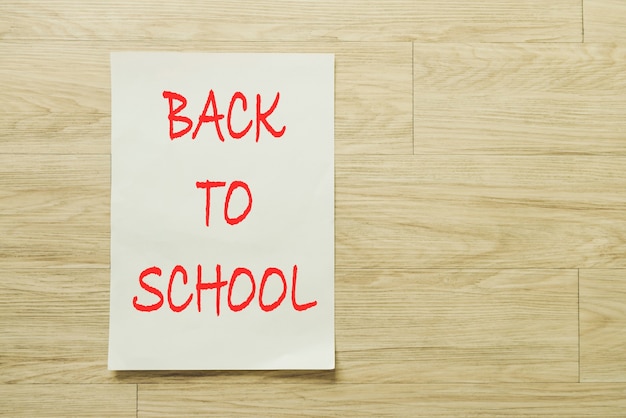 Free photo writing paper with back to school text over wooden background.