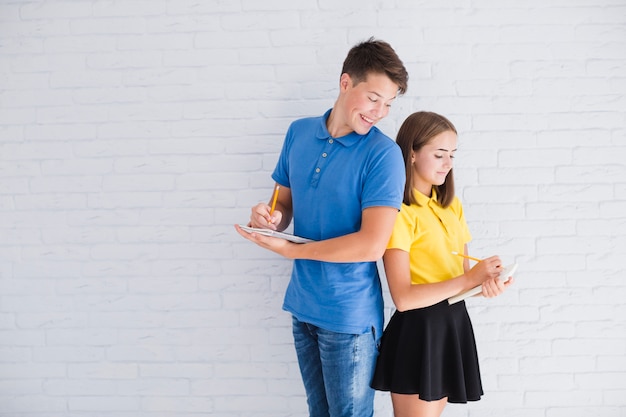 Writing teenagers standing back-to-back