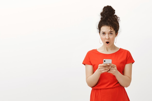 Free photo wtf who wrote this message. portrait of shocked displeased charming feminine woman in red dress