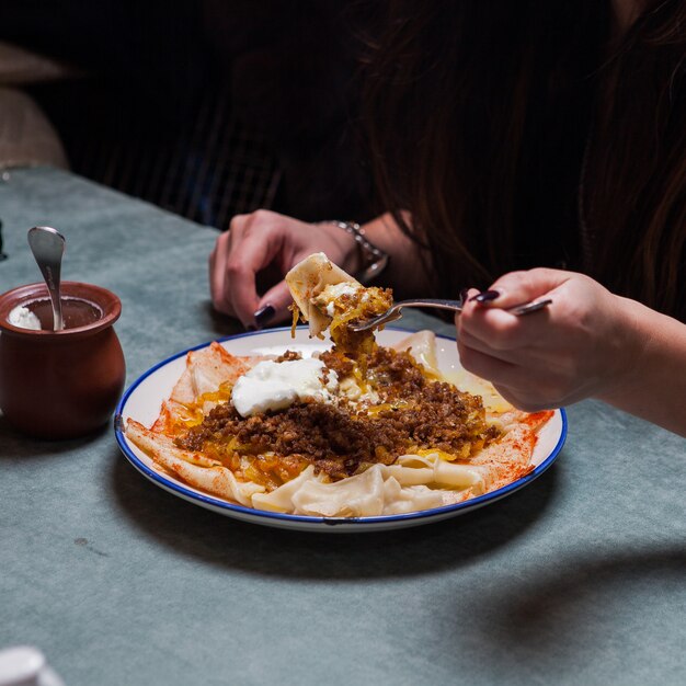 xengel with yogurt and human hand and fork in round plate