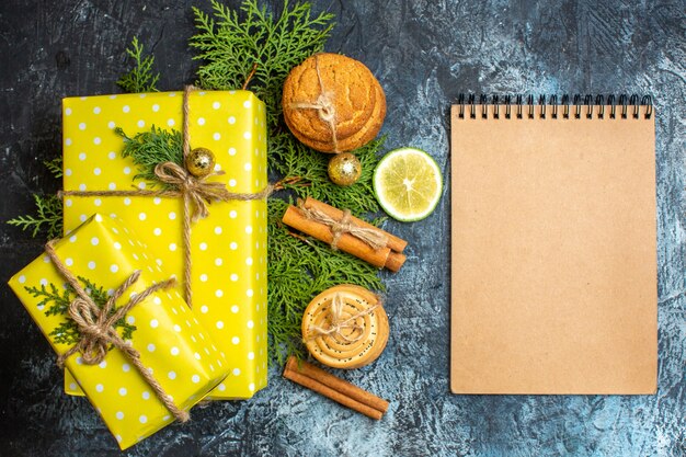 美しい黄色のギフトボックスと積み重ねられたクッキーレモンシナモンライムと暗い背景のノートブックとクリスマスの背景
