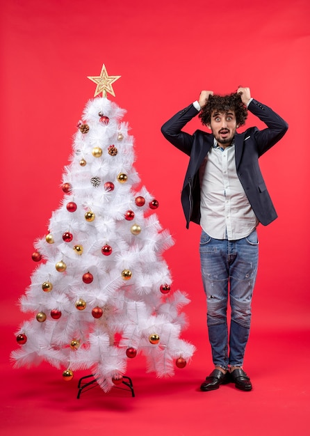 празднование Рождества с бородатым молодым человеком, измученным всем и очень нервным, стоя возле елки