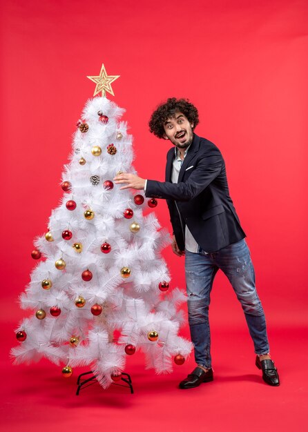 xmas celebration with happy surprised young man decorating Christmas tree with accesories