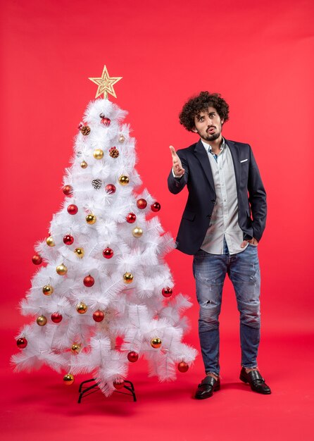 xmas celebration with serious young man welcoming someone standing near Christmas tree