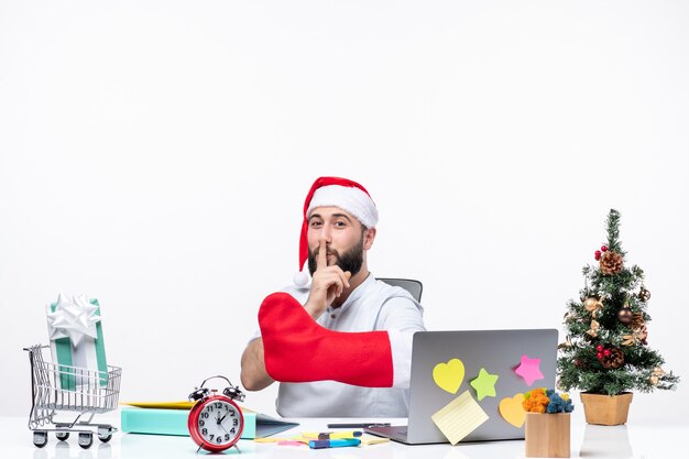 xmas mood with positive young adult with santa claus hat and wear christmas sock to his hand making silence gesture in the office