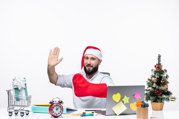 Foto gratuita umore natalizio con un giovane adulto positivo con cappello di babbo natale e indossa un calzino natalizio in mano in ufficio facendo il gesto finale