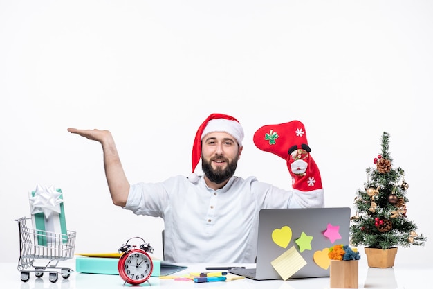 Umore natalizio con un giovane adulto positivo con cappello di babbo natale e indossa un calzino natalizio sulla sua mano che indica qualcosa