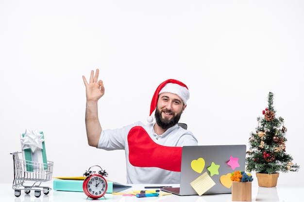 산타클로스 모자를 쓴 긍정적인 젊은 성인과 함께 크리스마스 분위기를 느끼고 사무실에서 세 개를 보여주는 크리스마스 양말을 손에 착용
