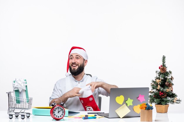 xmas mood with young adult with santa claus hat and opening his christmas sock looking at someone in the office