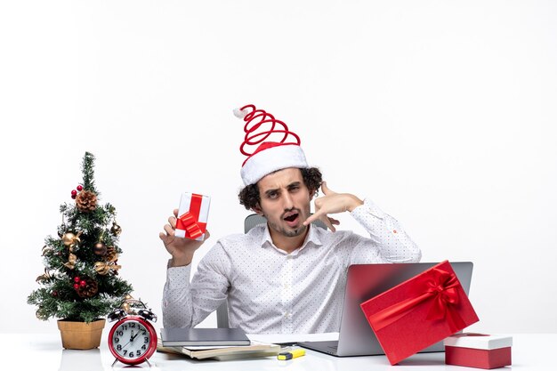 산타 클로스 모자와 그의 선물을 들고 젊은 사업가와 크리스마스 분위기 흰색 배경에 제스처 전화