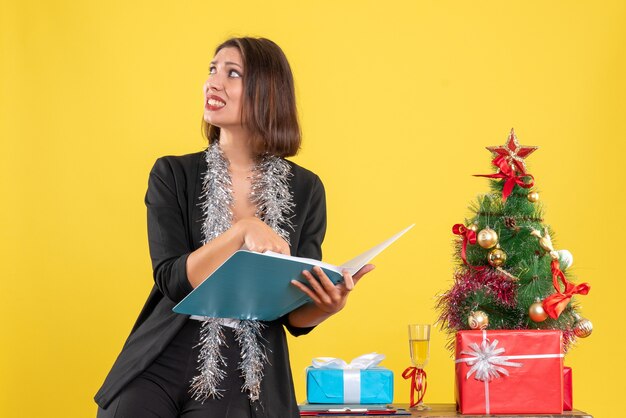 Xsmas mood with curious beautiful lady standing in the office and working alone in the office on yellow 