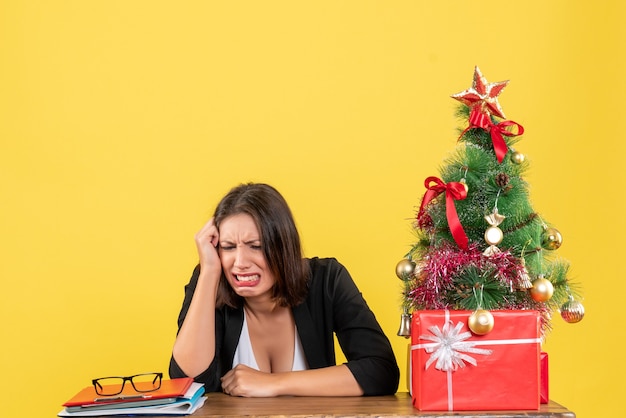 Free photo xsmas mood with young emotional beautiful woman focused on something carefully sitting at office