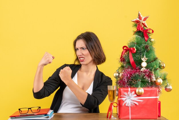 Xsmas mood with young emotional business lady sitting at a table in the office