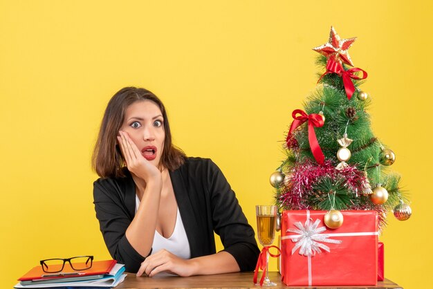 Рождественское настроение с молодой неудовлетворенной серьезной шокированной эмоциональной бизнес-леди на желтом