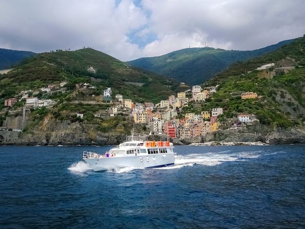 イタリア、リオマッジョーレの海岸沿い村の近くを航行するヨット