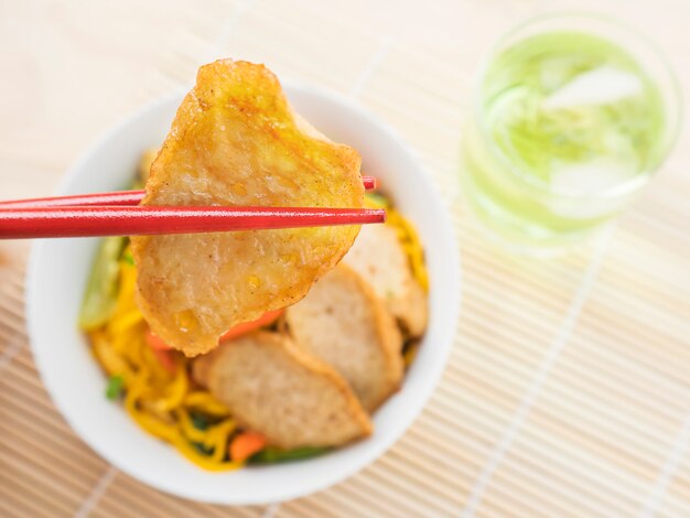 Yakisoba with chopstick and hand over bamboo pad