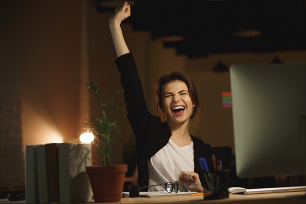 Yawning young woman designer sitting in office at night